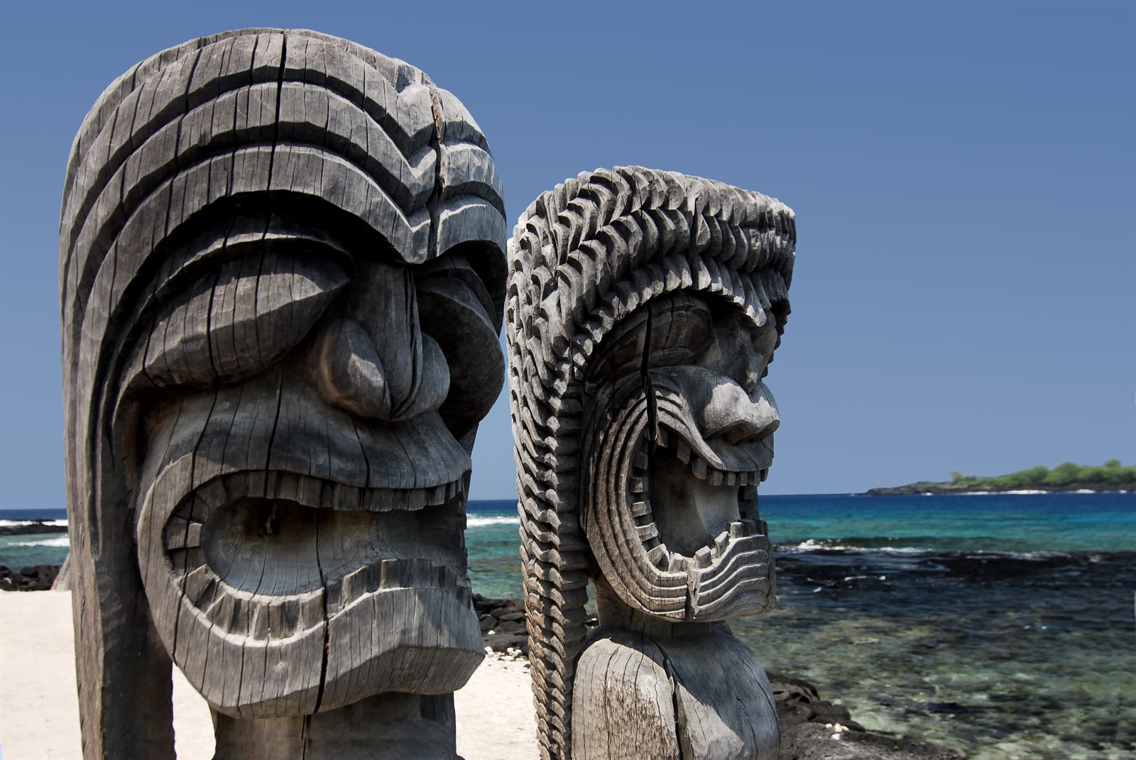 Carved wooden kiʻi images beside the sea at a Hawaiian place of refuge, a landmark of Hawaiian culture